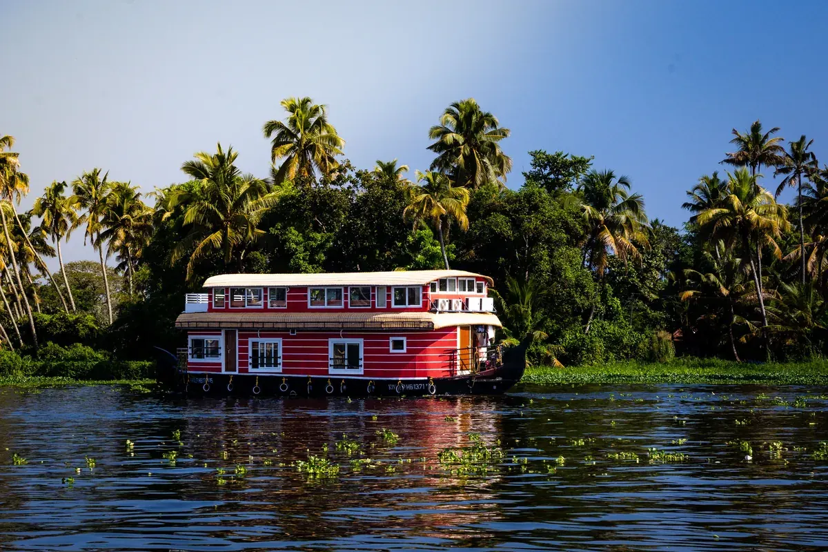 Traditional Kerala kettuvallam houseboat cruising the Alleppey backwaters past coconut palms